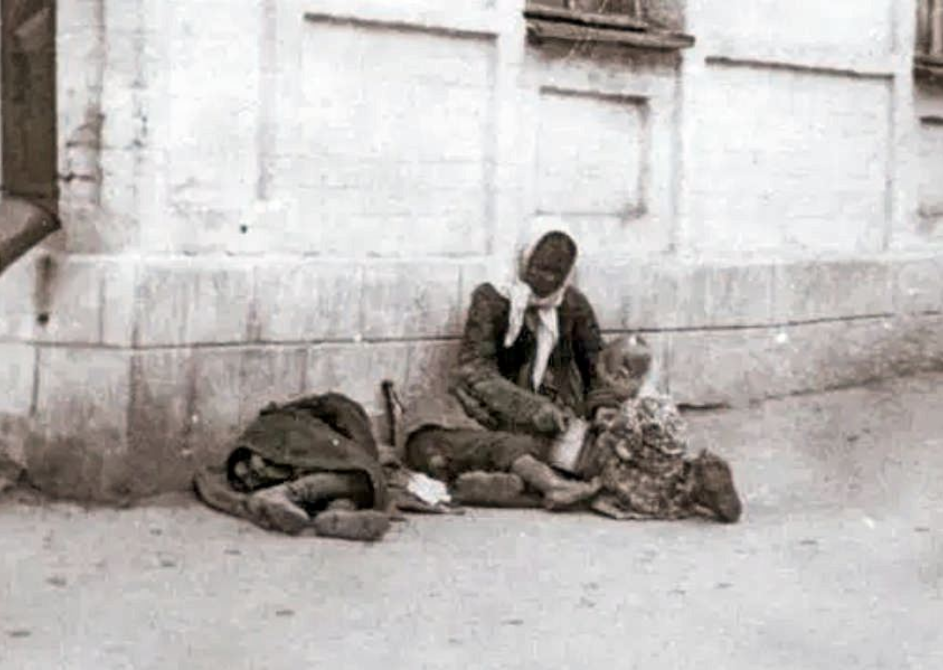 A mother sitting on a sidewalk in Kharkiv, feeds her starving children | Photo: Alexander Wienergberger, Kharkiv, 1933.